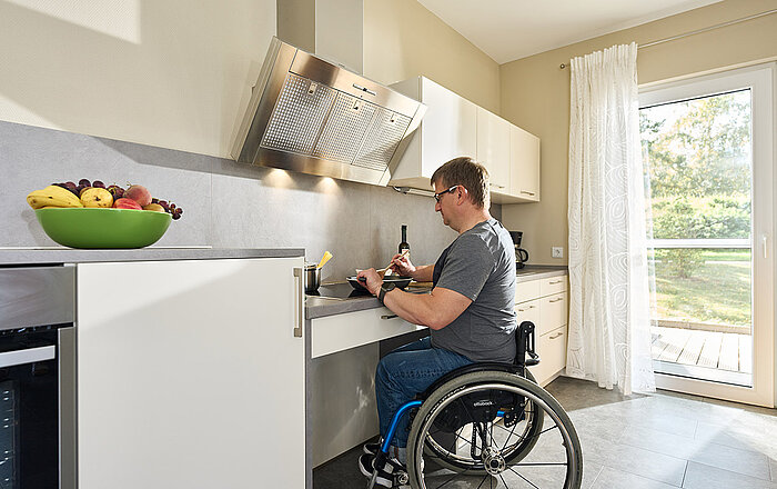 Rollstuhlfahrer kocht Essen in der Küche
