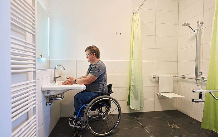 Rollstuhlfahrer wäscht sich die Hände im Bad
