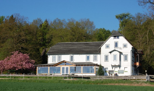 Hotel mit weißer Fassade und großer Grünfläche vor dem Haus