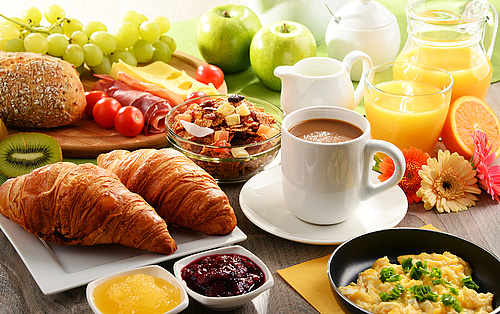 Frühstück mit Croissants, Obst, Kaffee, Marmelade und Spiegelei