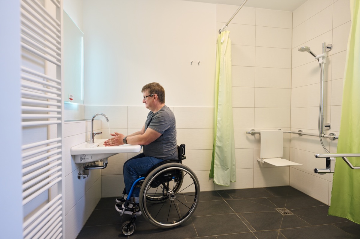 Rollstuhlfahrer im barrierefreien Badezimmer des Ferienhauses